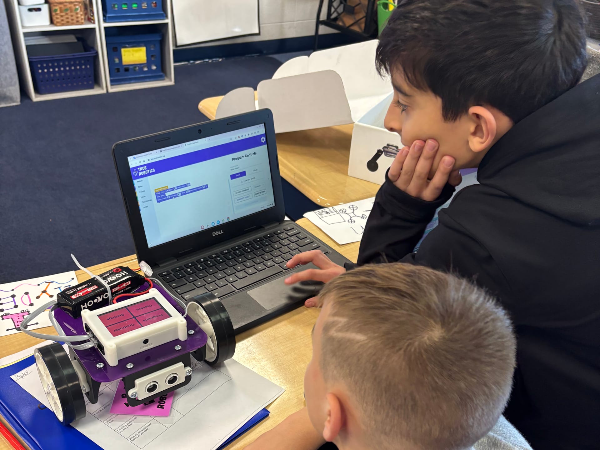 Two students at a classroom desk program a Pilot robot on a Chromebook running True Robotics Playground